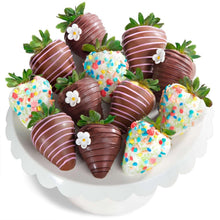 Chocolate-covered strawberries with white stripes, sprinkles, and green leaves on heart tray