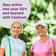 Two older women outdoors wearing helmets and holding bicycle handlebars, smiling