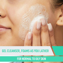 Person cleansing face with foamy cleanser, lather rising over skin