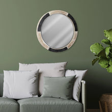 Round wood mirror with black textured rim and silver reflective glass above sofa