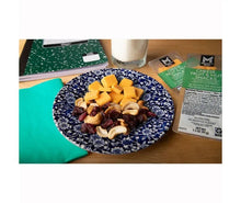 Snack plate with cheese cubes, nuts, and dried fruit beside a snack pack