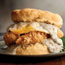 Breaded cutlet with white gravy on split biscuits, topped with herbs.