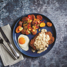 Plate with breaded cutlet topped with white gravy, fried egg, and vegetables.