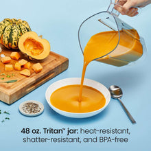 Ice-crushing blender pouring orange smoothie into a bowl