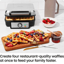 4-slice Belgian waffle maker with golden waffles, berries on plates and tray