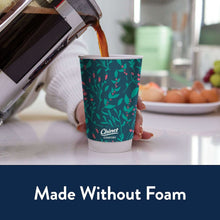 Insulated 16 oz cup with black lid on table; green berry pattern sleeve.