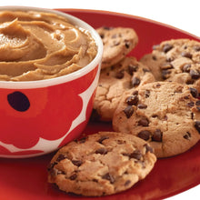 Cookies with chocolate chips beside a red smile mug with light-brown spread