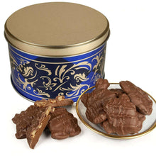 Blue and gold gift tin with chocolate pecan clusters in a white serving dish