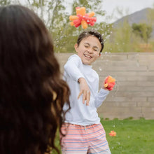 Reusable sponge balls bursting from a child’s hands, colorful foam pieces.