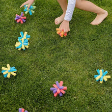 Reusable sponge balls scattered on grass, bright pastel foam flower shapes.