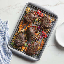 Grey nonstick roasting pan in oven with sliced steak and roasted vegetables