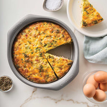 Grey nonstick round pan with a baked egg quiche and herbs