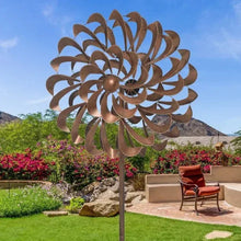 Metal pinwheel wind spinner with brown pinwheel blades and round center on garden pole.
