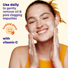 Facial cleanser used on cheeks; woman smiles with hands pressed to face.