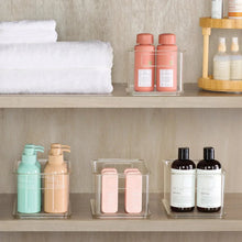 Clear plastic storage bin set with hinged lids, holding bottles and jars