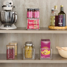 Clear plastic organizer bins with hinged lids, arranged on a countertop shelf