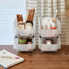 Two-tier clear stacking storage bins with thread spools, craft supplies, and jars
