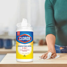 Clorox disinfecting wipes canister with white wipe and hands holding it