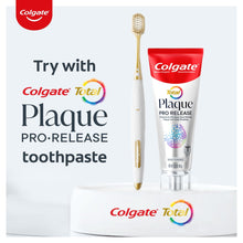 Manual toothbrush with gold handle beside Colgate Total Plaque pro release toothpaste tube