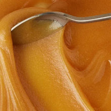 Raw manuka honey texture in a spoon, golden amber color.