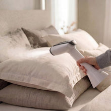 Handheld garment steamer steaming light bedding with nozzle over wrinkles