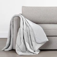 Light gray quilted cooling throw draped over sofa arm