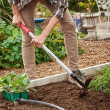 Red-and-gray garden digging tool used to loosen soil along a planting row