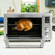 Silver air fryer toaster oven with whole chicken inside on wire rack
