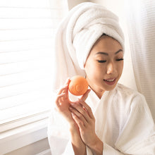 Kids bath bomb held by person in white towel, orange round bomb on palm