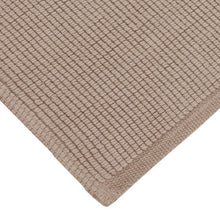 Beige cotton woven bath mat corner close-up with textured surface