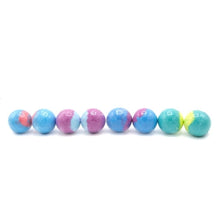 Assorted round bath bombs with blue and pink tones, plus green end pieces on white