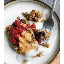 Bowl of yogurt topped with granola, berries, and peanut butter drizzle