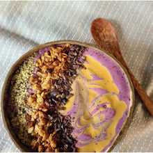 Smoothie bowl with purple and yellow swirls, granola, and chocolate nibs