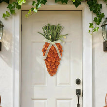 Carrot swag decoration hanging on a door with orange carrot and green leaf top