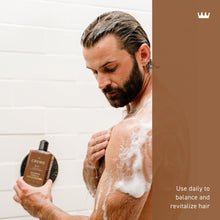 Cremo 2-in-1 shampoo and conditioner bottle in hand, man lathered in shower