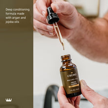 Hands dispensing beard oil from dropper onto another hand