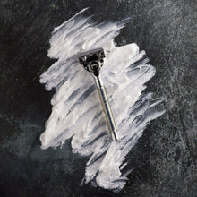 Razor with blade head partially covered by white shaving foam