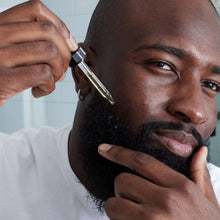 Man applying beard oil with a dropper to his beard