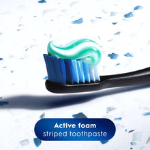 Mint-striped toothpaste on toothbrush bristles, active foam texture