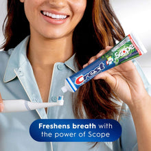 Crest Premium Scope mint toothpaste tube held by a woman