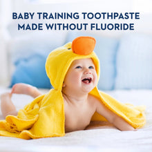 Baby in yellow hood towel with a training toothbrush in mouth