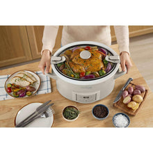 Crock-Pot slow cooker with lid open and handles, meal inside the pot