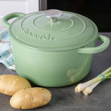Pistachio green dutch oven with lid and side handles on a countertop