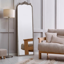 Full-length arch floor mirror with black ornate filigree frame and beaded border