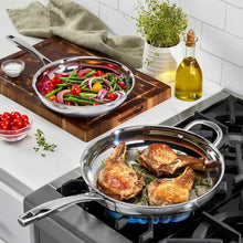 Two stainless steel skillets on gas burner cooking chicken and vegetables