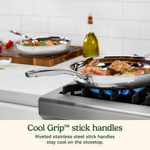 Stainless steel skillet with riveted stick handle and cooking food in shallow pan