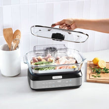 Digital glass steamer with clear lid being lifted, showing food inside