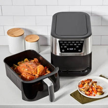 Air fryer with removable basket out, holding roasted food; black handle and digital control panel
