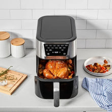 Air fryer with open basket holding roasted chicken, black handle, and digital control panel