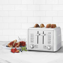 4-slice toaster with bread rolls in slots, with fruit and spreads nearby